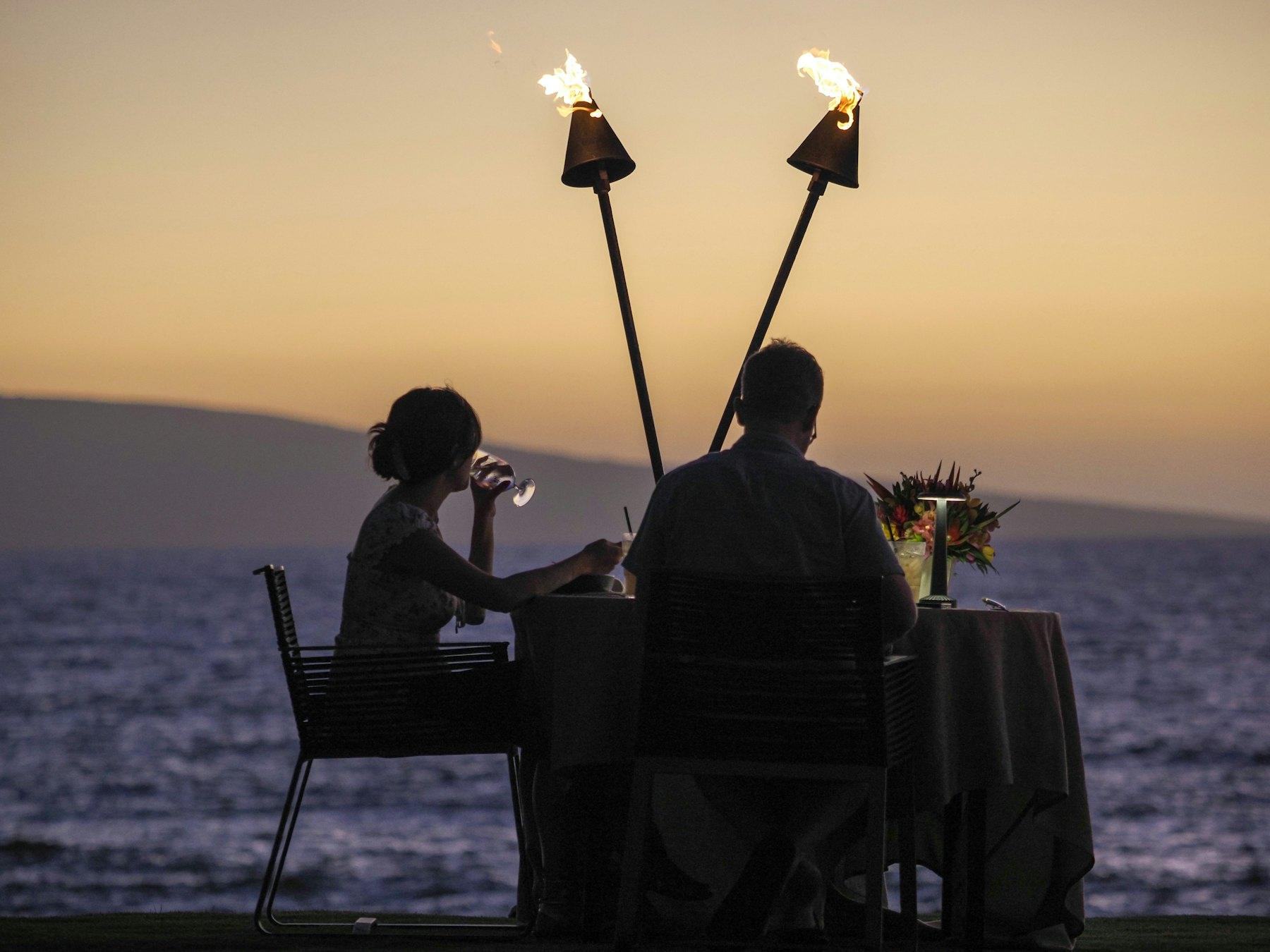 Ein Paar beim Abendessen am Wasser bei Sonnenuntergang