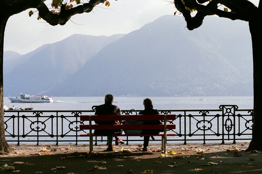 Ein Paar auf einer Bank mit Blick auf See und Berge im Herbst